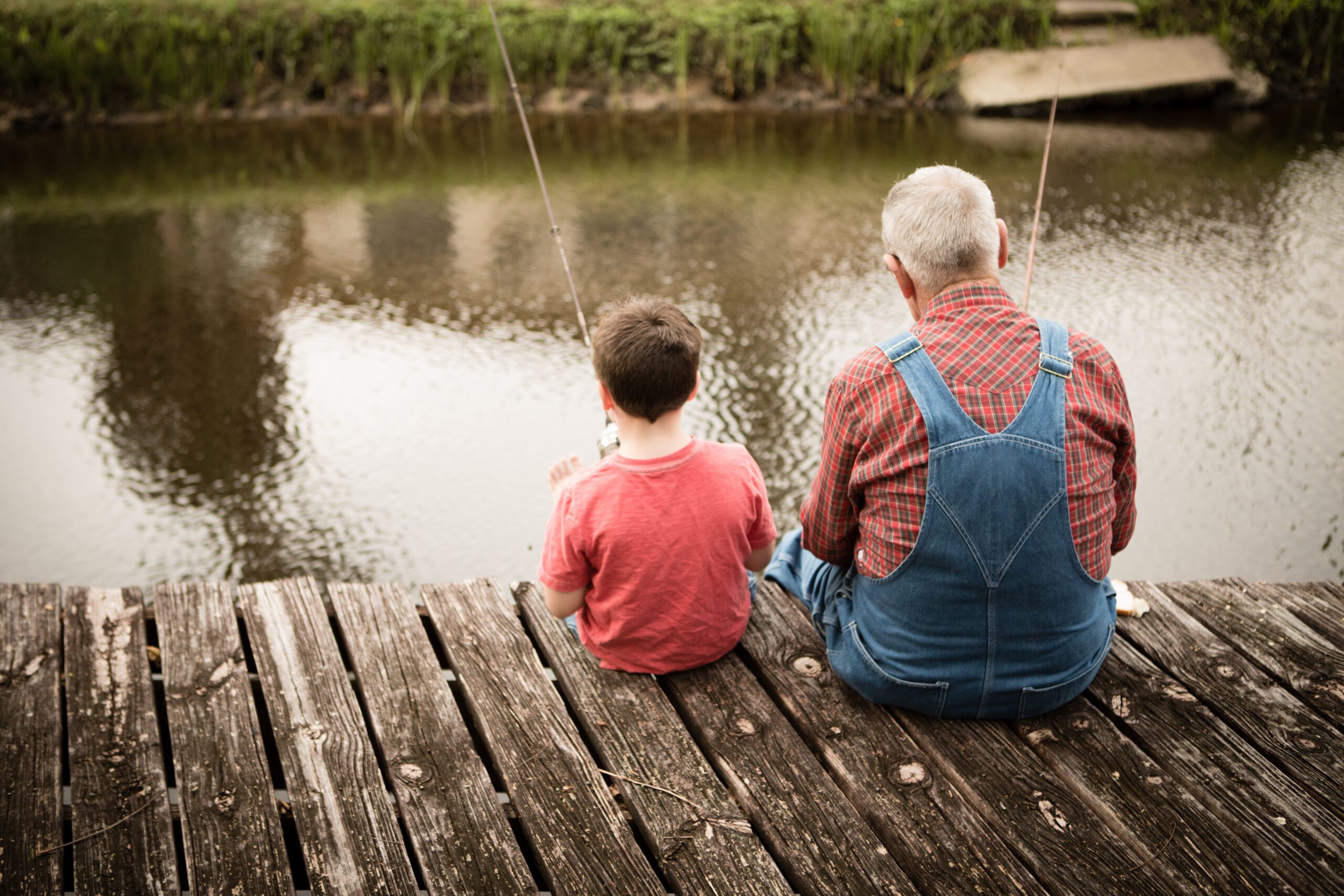 Dad with his Son fishing on a pier at dawn