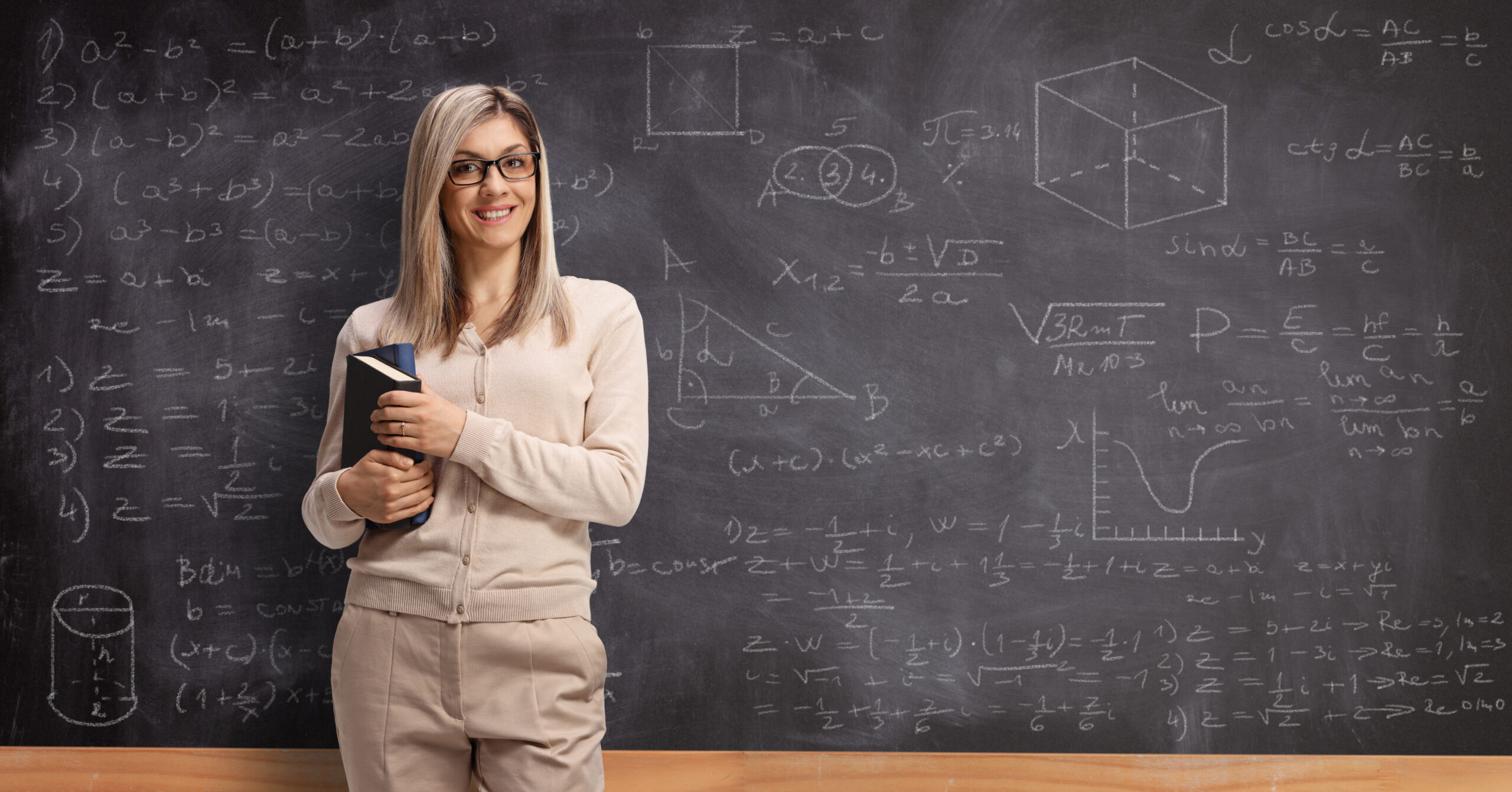 Teacher standing in front of a chalk board with advanced equations on it