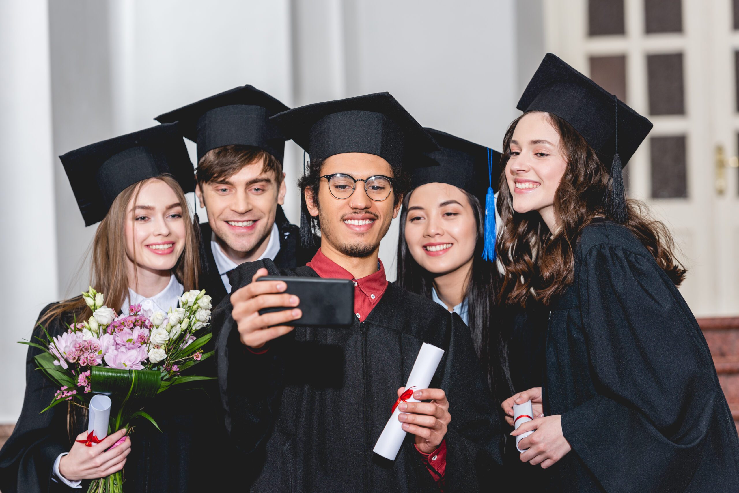A group of graduates in cap and gown taking a selfie.